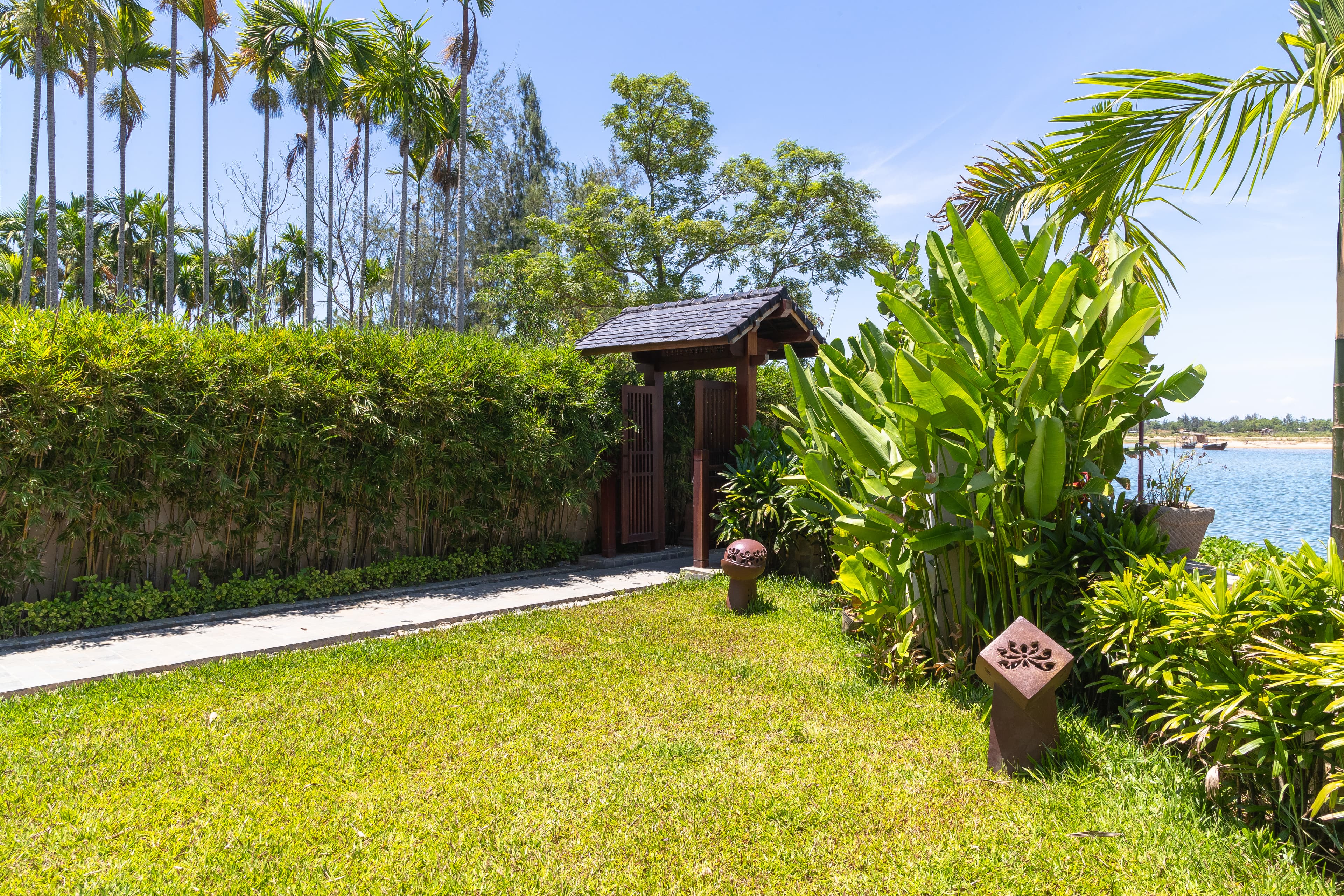 Anonymous male fisher rowing boat on river near large lift net against cloudy sunset sky in Vietnam