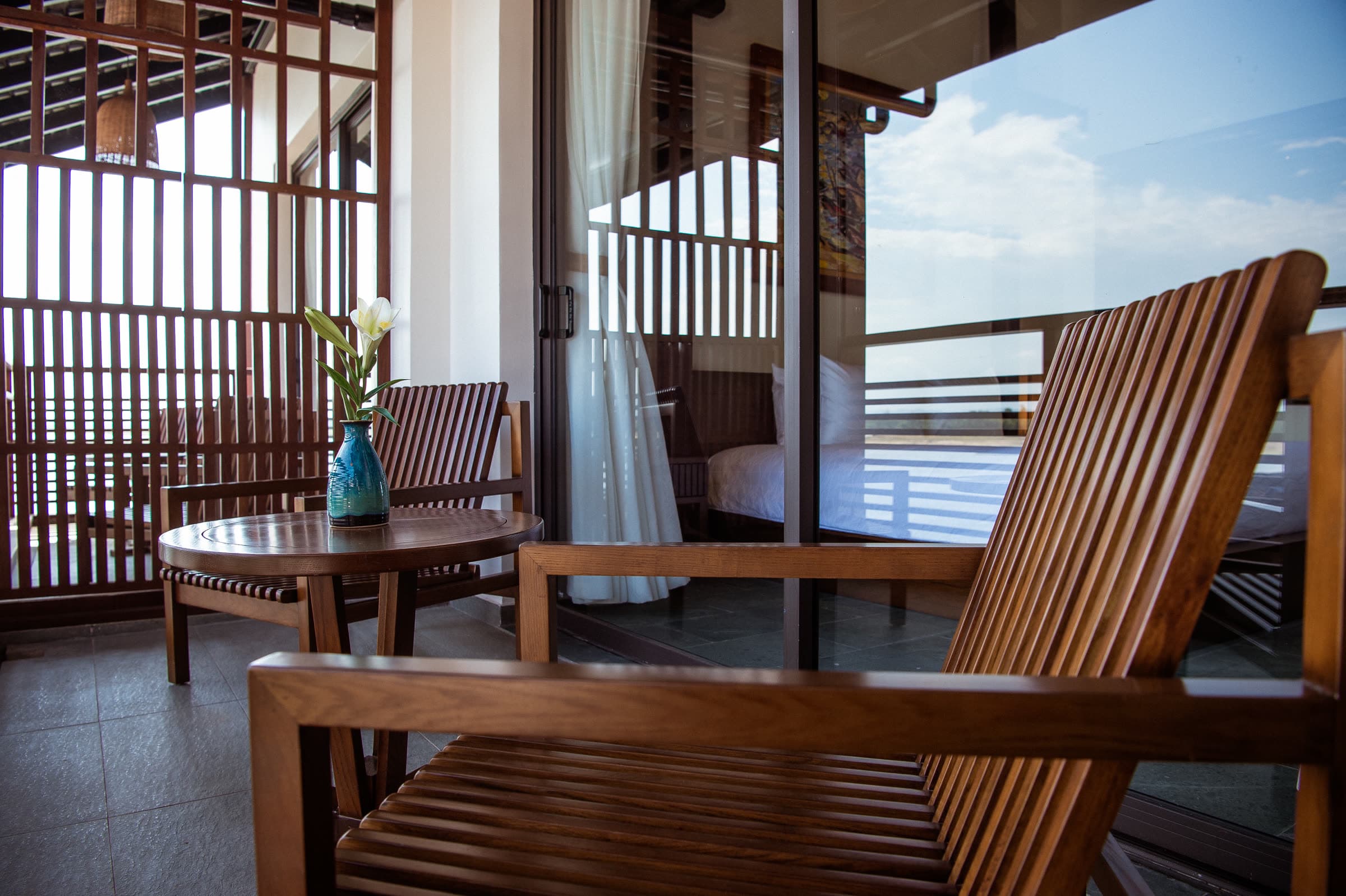 Balcony chairs at a riverview room, the Thu Bồn River beyond the timber railing