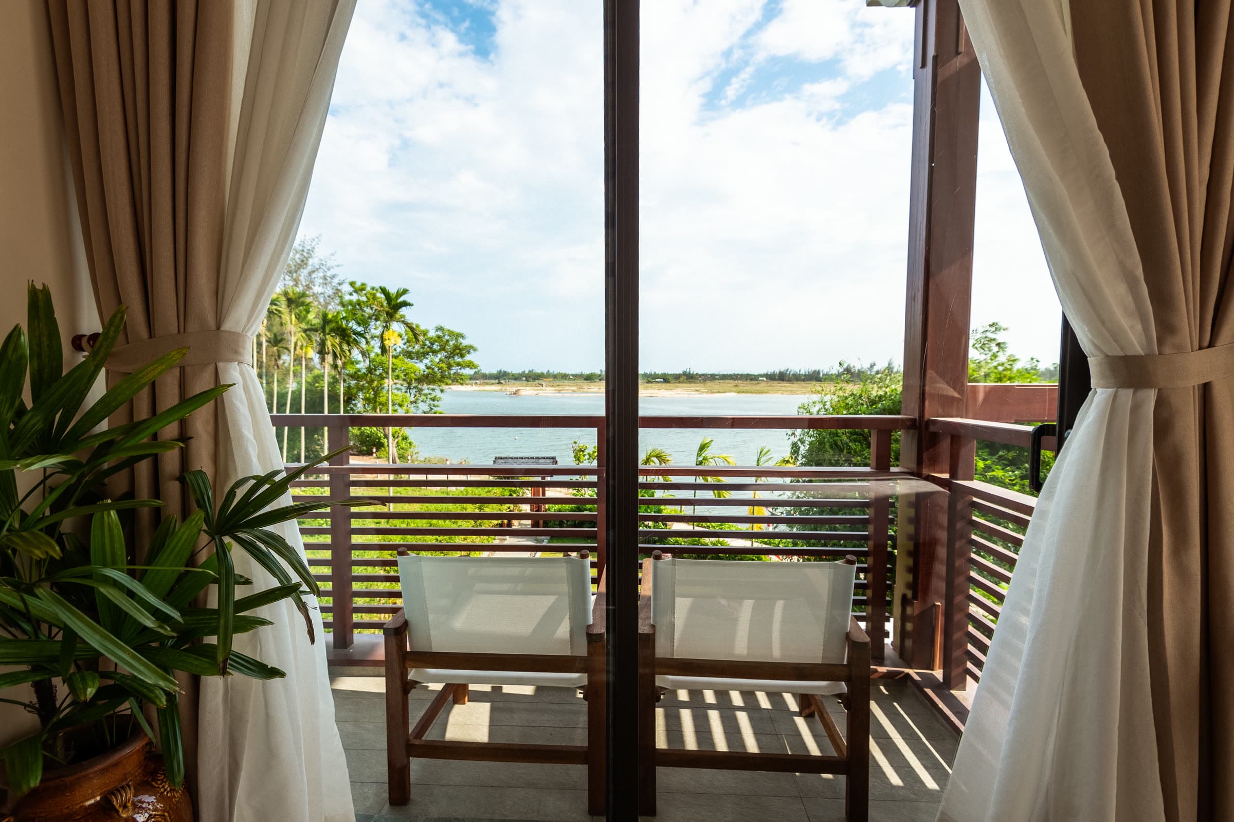 Two timber chairs on the River Suite balcony looking out over the Thu Bồn River