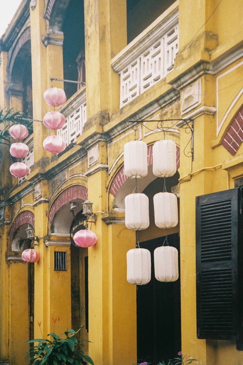 Hội An Old Town pink and white silk lanterns hanging in front of historic yellow ochre colonial buildings — neighbourhood character of Minh An.