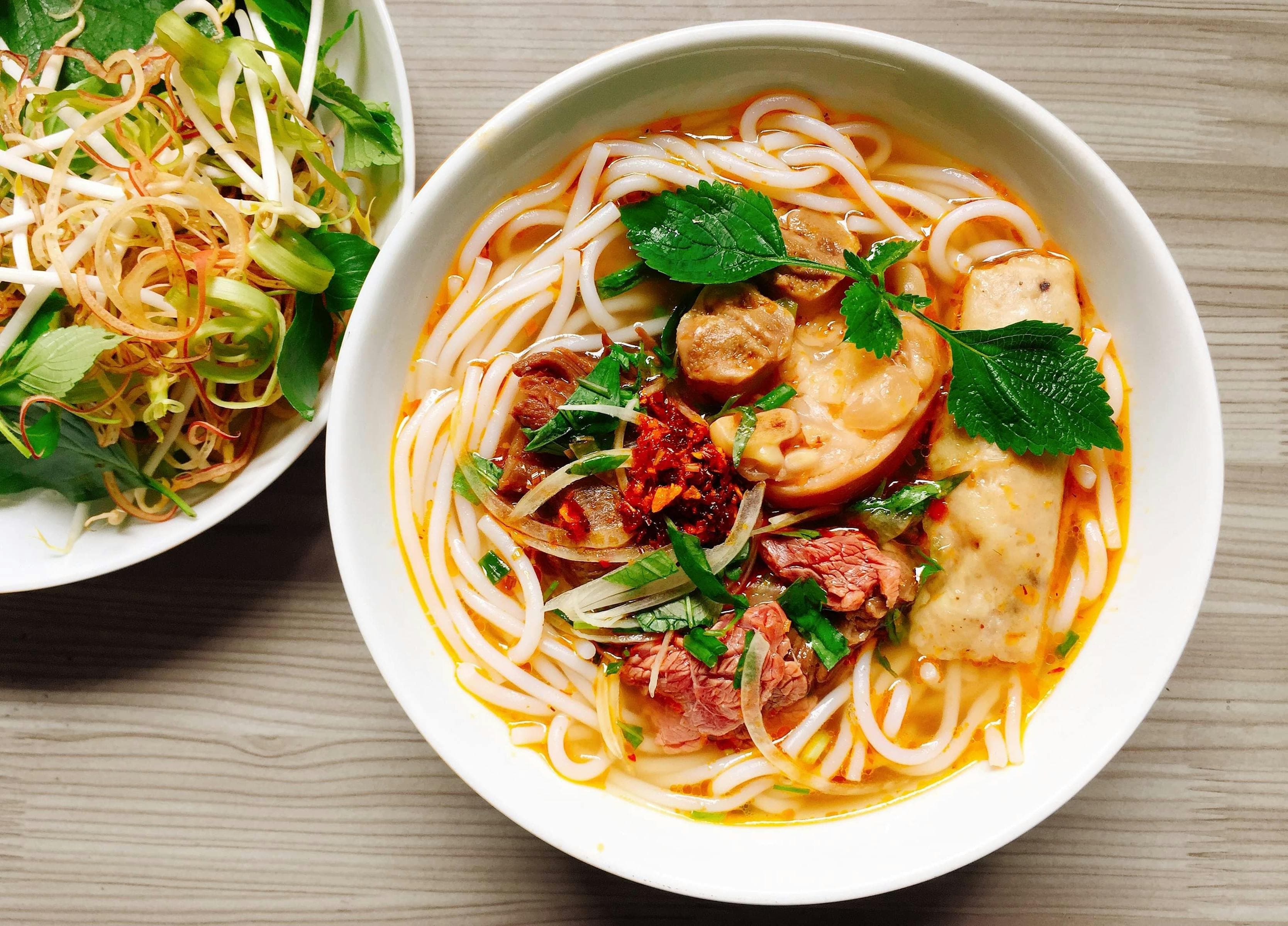 Vietnamese noodle bowl with rice noodles, beef, fresh herbs, lime, and chili — the visual language of Hội An central-Vietnam cuisine