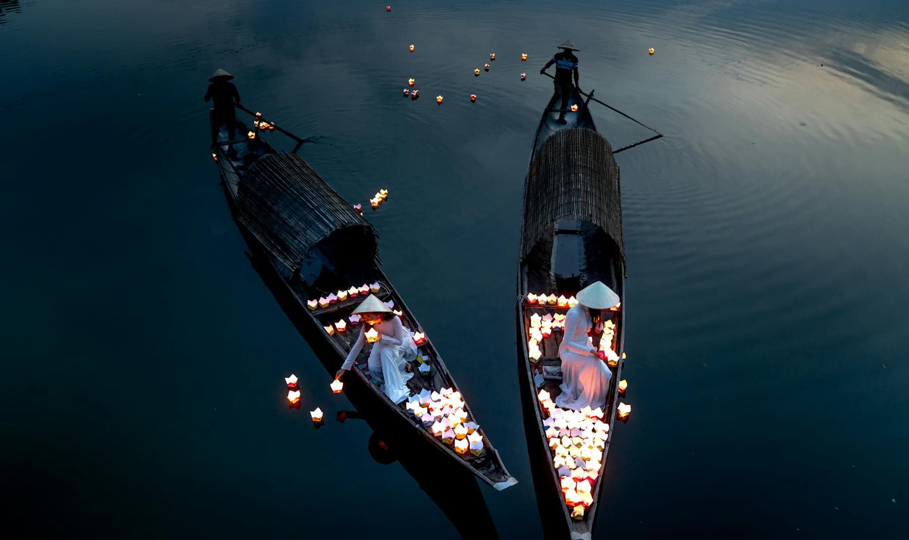 Silk lanterns reflected on the Thu Bồn river at Hội An at night — the quiet riverside evenings that lead most couples to choose Hội An over Đà Nẵng for a honeymoon, from Nghê Prana at Cẩm Nam.